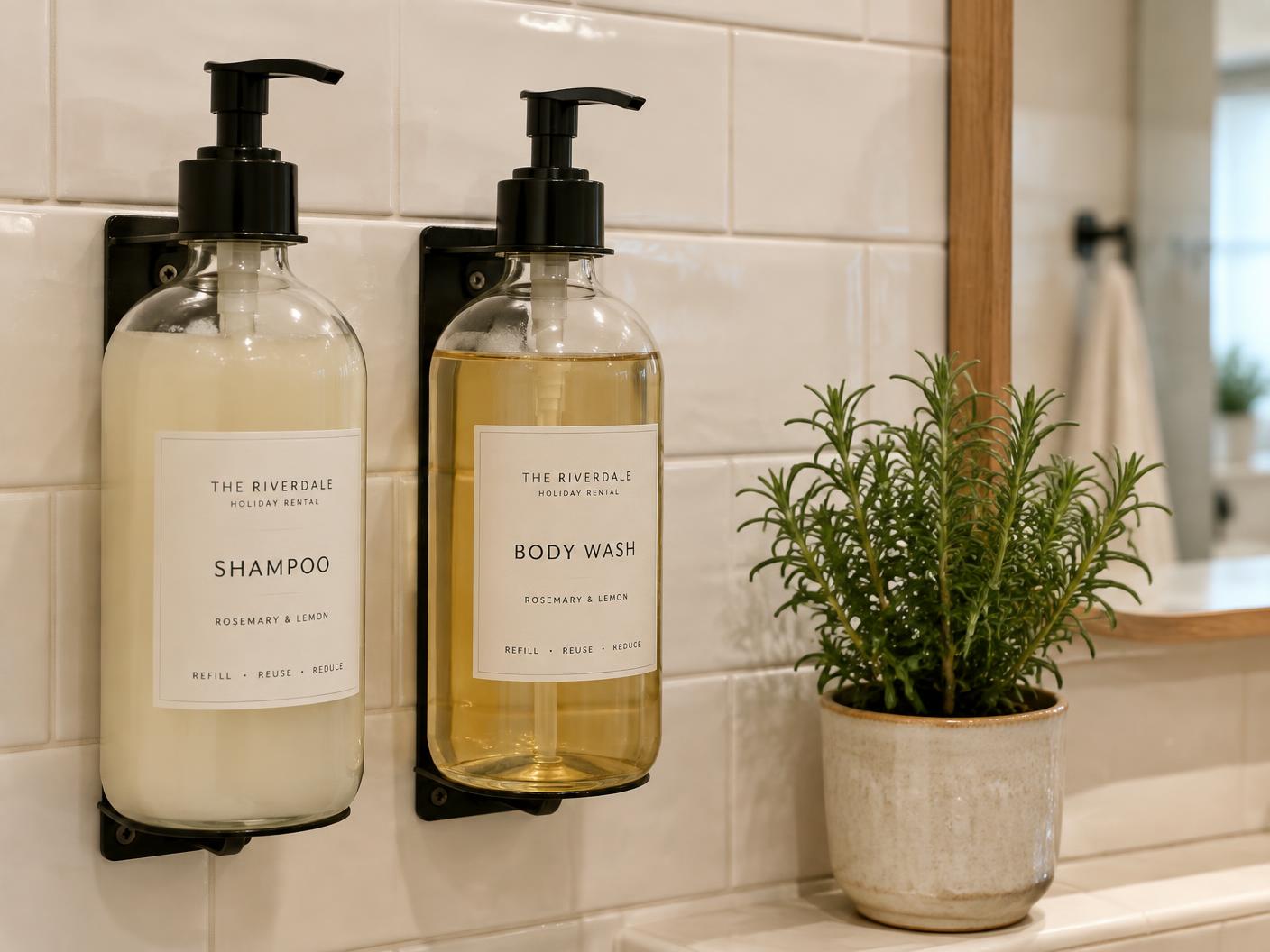 Refillable glass pump bottles of shampoo and body wash in a rental bathroom, no single-use plastic